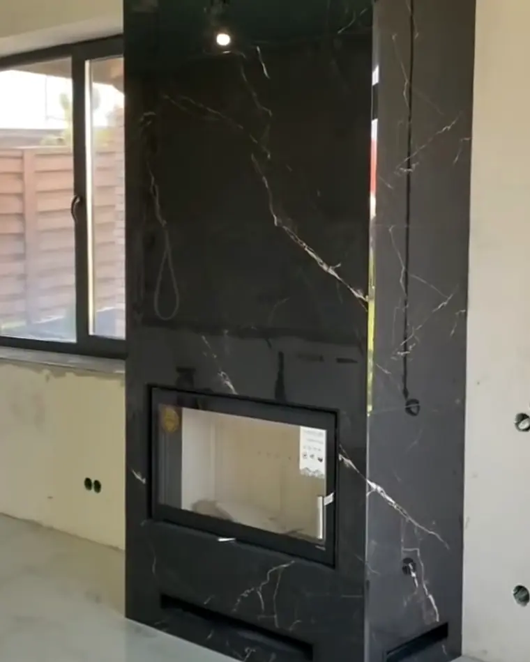 Cheminée-Wand mit grossformatigen Platten in schwarzer Marmoroptik bekleidet